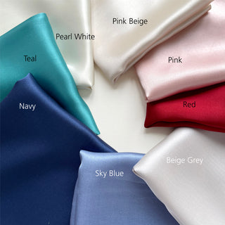 Collection of folded plain silk satin scarves in various colours with labels on a white background