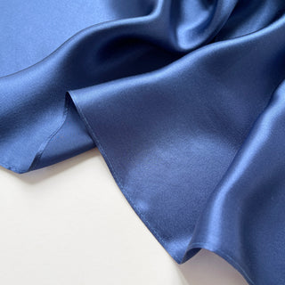 Close-up of a navy blue silk satin scarf with smooth, lustrous finish showing the scarf's soft texture and rich colour