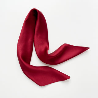 Red silk satin scarf on a light gray background
