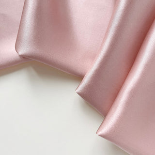 Close-up of a pink silk satin scarf with smooth, lustrous finish showing the scarf's soft texture and rich colour
