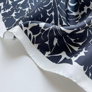 Close-up of black floral silk scarf, 65cm square with hand-rolled ice white border.