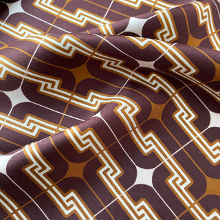 Silk scarf with retro 70s geometric pattern in burgundy, amber, and cream, featuring distinctive Greek key designs on luxurious twill fabric.