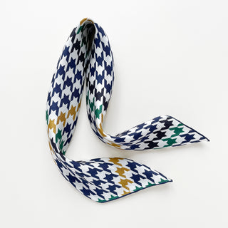 Luxurious silk scarf with classic houndstooth pattern in navy, green, and gold on white background, elegantly draped to showcase texture