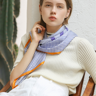 Women’s silk square scarf in blue checks and houndstooth with orange border, hand-rolled edges, styled around the neck for a perfect finishing touch.