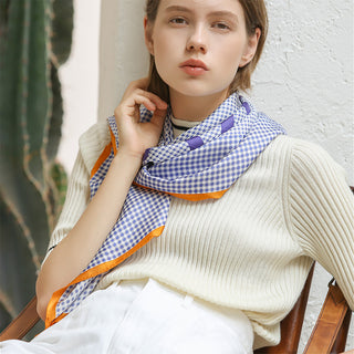 Women’s silk square scarf in blue checks and houndstooth with orange border, hand-rolled edges, styled around the neck for a perfect finishing touch.