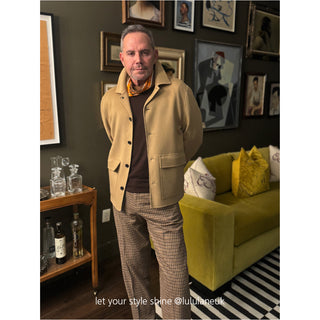 Brown and orange plaid cashmere silk scarf styled with tan coat, dark sweater and patterned pants in elegant home interior setting