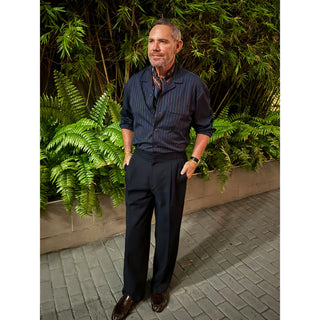 Man wearing a navy paisley silk square scarf by LuluLane in striped navy shirt and navy trousers showcasing a sharp and refined look.