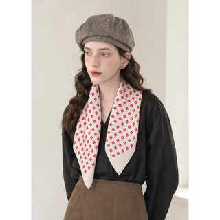 Woman wearing an ivory and red mini floral silk square scarf loosely around her neck, styled with a black blouse, brown skirt and tweed beret.