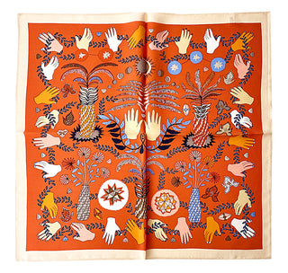 Orange Tarot Garden silk scarf with mystical design featuring illustrated hands, botanical elements, celestial symbols, and geometric patterns on a vibrant orange background with cream border.