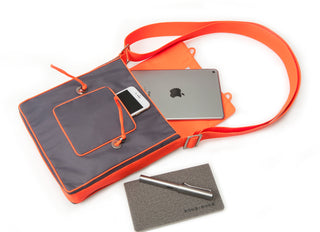 Orange and gray messenger bag with bright trim showing interior capacity with iPad, smartphone, and notebook, featuring adjustable crossbody strap