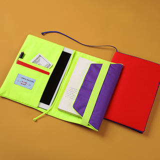 Colorful recycled notebook cover with neon green interior, red exterior, and purple accents, showing compartments for tablets, notebooks, and cards