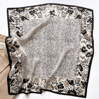 Black Twilight Blossom silk scarf featuring elegant floral border with black flowers and gold accents on cream background with speckled center pattern