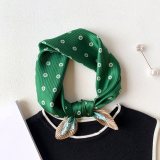 Green silk bandana with white floral medallion pattern tied elegantly around a mannequin neck, featuring a decorative border and shiny silk texture