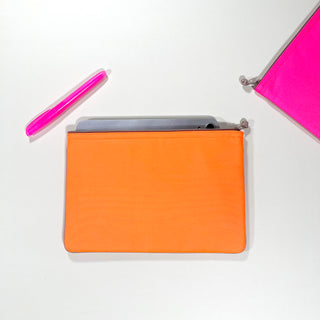 Vibrant recycled iPad case in neon orange with gray device visible inside, alongside bright pink pen and corner of pink case against white background