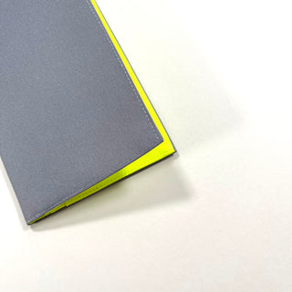 Gray minimalist passport holder with neon yellow edging, made from recycled RPET material, featuring clean lines and slim design