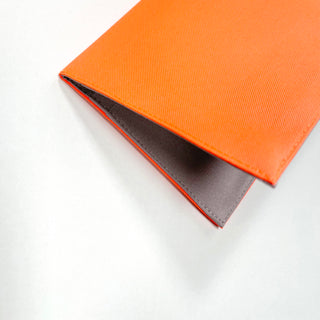Bright orange minimalist passport holder made from recycled RPET material with gray interior lining, showing clean piping detail and slim profile