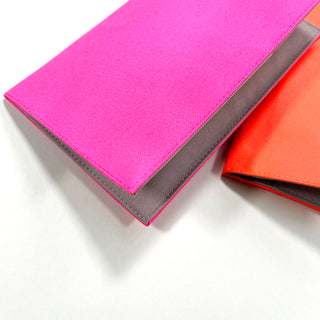 Bright pink and orange recycled RPET passport holders with gray trim detail showing the neat piping edge and minimalist design