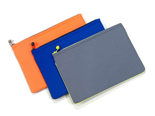 Three recycled waterproof iPad cases arranged in a row - bright orange, royal blue, and gray with neon trim, each featuring a YKK zipper closure