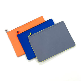 Three minimalist recycled laptop sleeves in orange, royal blue, and gray with colorful piping and decorative zipper pulls for 13/14-inch MacBooks