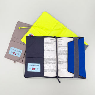Three recycled notebook covers in navy, taupe, and neon yellow, showing organizational compartments with book inserted, featuring Urban Walkers logo tags
