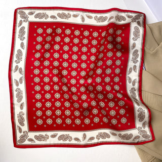 Red silk neckerchief with octagonal star medallion pattern and cream-colored paisley border, displayed flat showing luxurious texture
