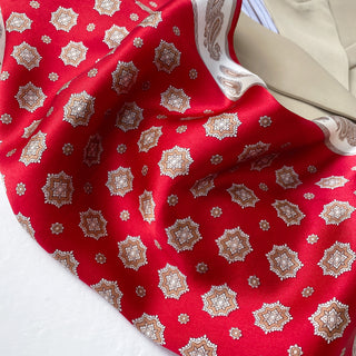 Luxurious red silk neckerchief with ornate octagonal star medallion pattern in beige and white, featuring a contrasting white border with paisley design
