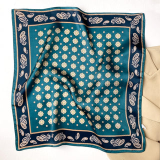 Luxurious teal silk neckerchief with gold octagonal medallion pattern, navy blue paisley border, and elegant gold trim displayed on beige fabric