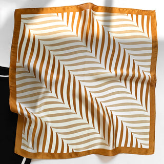 Luxurious silk bandana with geometric golden caramel stripes on cream background, featuring burnt orange border and modern leaf-like pattern