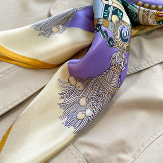 Luxury silk scarf in pale yellow and lilac featuring vintage decorative pattern with ornate tassels and gold trim, showing elegant sheen