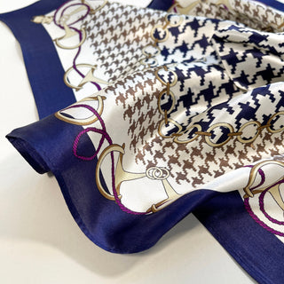 Indigo blue silk scarf featuring classic houndstooth pattern in brown and navy, decorated with gold chain design and purple accents on cream background
