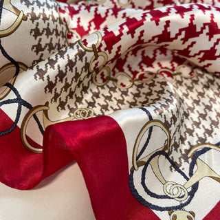 Luxurious silk scarf featuring houndstooth pattern in brown and cream with vibrant red accents, gold chain motifs, and navy blue details