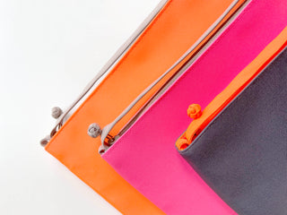 Three eco-friendly RPET crossbody phone wallets with traditional Chinese button detail, shown in orange, pink, and navy colors with YKK zippers.