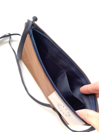 Open tan crossbody phone wallet showing navy blue interior with card sleeve pockets and YKK zipper, featuring traditional Chinese button closure detail