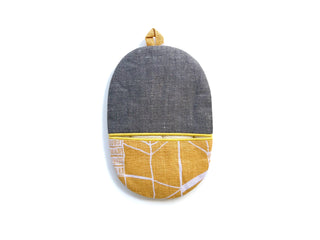 Handmade linen oven mitt with navy herringbone pattern top and mustard yellow geometric patterned bottom, featuring hanging loop and piped edges.
