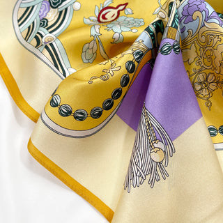 Luxurious silk scarf in yellow and lilac with vintage decorative pattern featuring floral motifs and ornate details, elegantly draped to show shimmering fabric texture