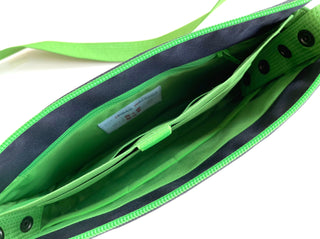 Interior view of bright green recycled crossbody bag showing multiple organizational pockets, navy blue lining, and YKK zipper closure with brand tag inside.