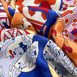Luxurious silk scarf with medieval design featuring vibrant red, blue, orange, and pale yellow colors in an ornate pattern with decorative motifs.