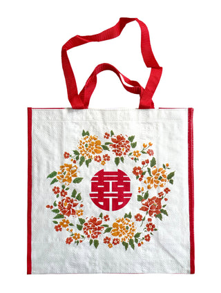 White shopping tote bag with red handles featuring traditional Chinese floral design in orange and red with green leaves surrounding a red double happiness symbol