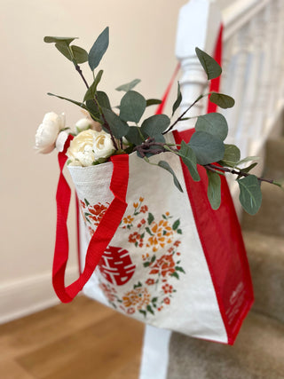 White and red tote bag with Chinese character 福 and floral pattern, filled with eucalyptus and white flowers, featuring dual-length handles
