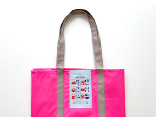 Bright pink recycled large tote bag with gray handles and decorative label showing urban lifestyle icons, displayed against white background