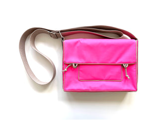 Bright pink eco-friendly messenger bag with front pocket, contrasting beige trim, and adjustable brown crossbody strap on white background
