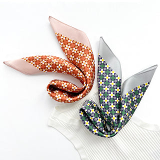 Two silk bandanas with retro geometric mosaic patterns - pink and orange on left, gray and green on right - displayed on white fabric.