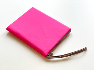 Bright pink recycled Kindle case with YKK zipper and wrist strap, featuring a slim rectangular design for Kindle devices and travel essentials