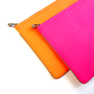 Vibrant recycled laptop sleeves in orange and hot pink with neat piping edges and handcrafted zipper pulls, designed for 13-14 inch MacBooks