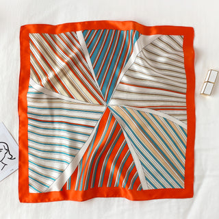 Square silk scarf with bright orange border and sunburst pattern featuring navy, orange, and beige stripes radiating from center