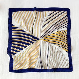 Square silk scarf with navy border featuring sunburst pattern of orange, navy and white stripes radiating from center, displayed flat
