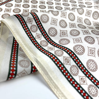 Cream silk neckerchief with decorative medal pattern featuring brown circles and squares, bordered with red and black diamond trim
