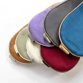 Collection of luxury double-sided silk sleep masks in various colors including deep red, blue, purple, gray, cream, and light brown, with elegant trim and clasps